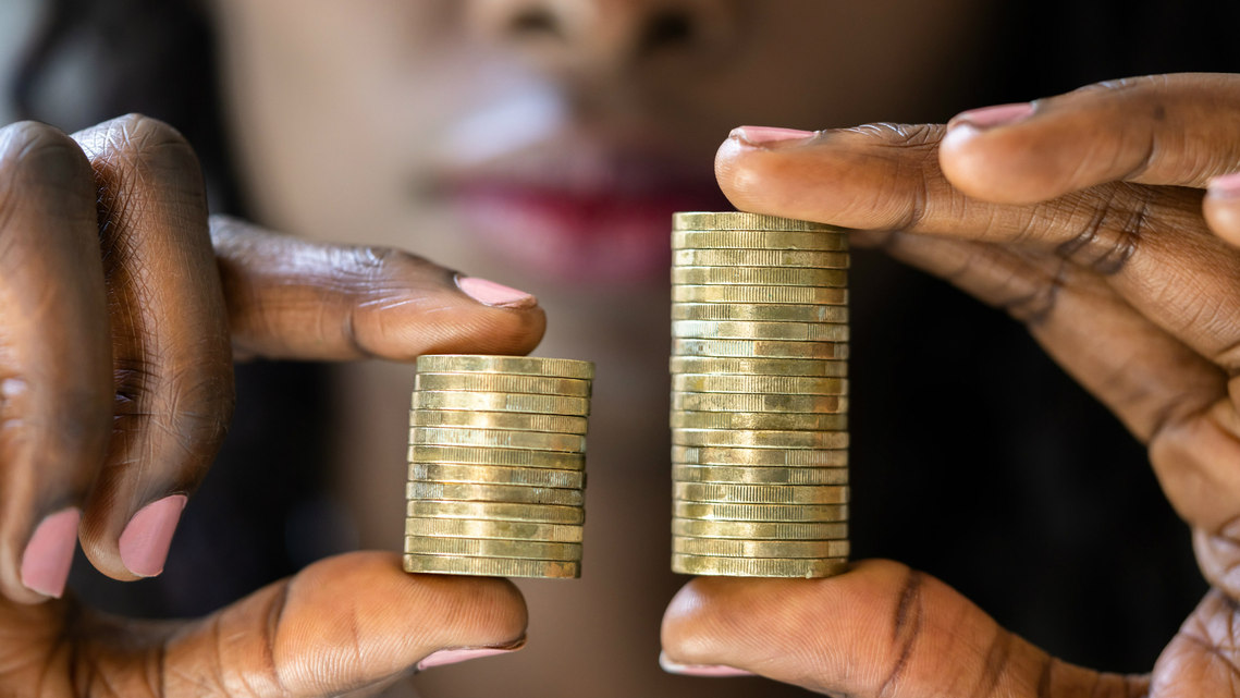 Photo of a woman's hands in close up holding a different number of pound coins in each