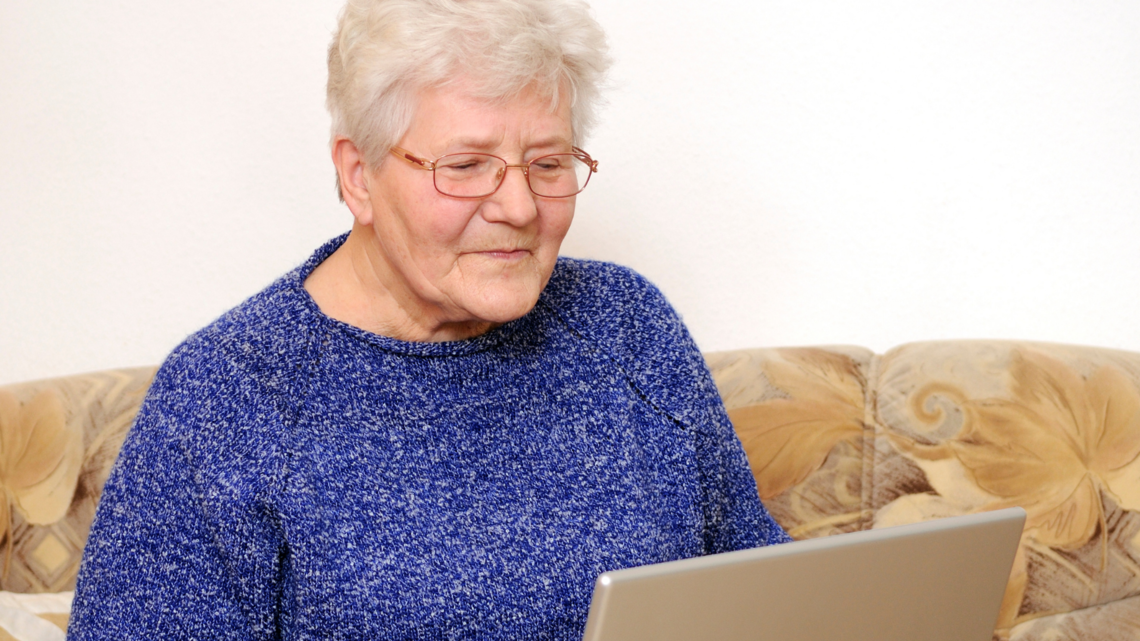 Photo of a woman in close up sitting on her sofa working on a laptop